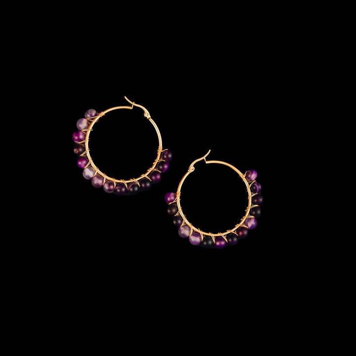 Hoop earrings with purple amethyst gemstones on a black background