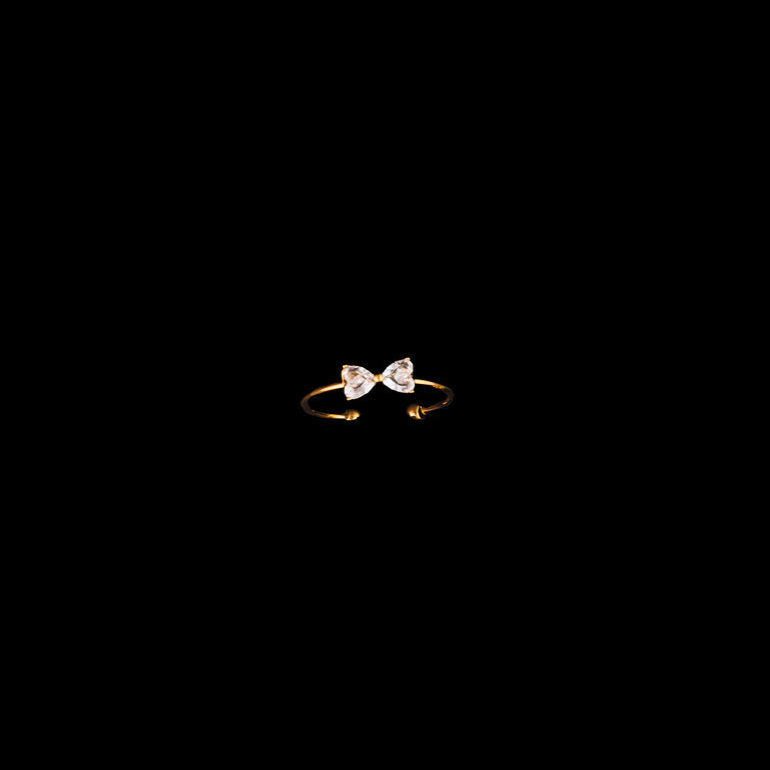 Gold ring with a bow design on a black background