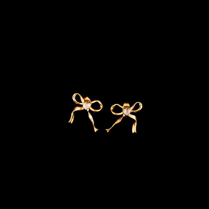 Gold bow-shaped earrings on a black background