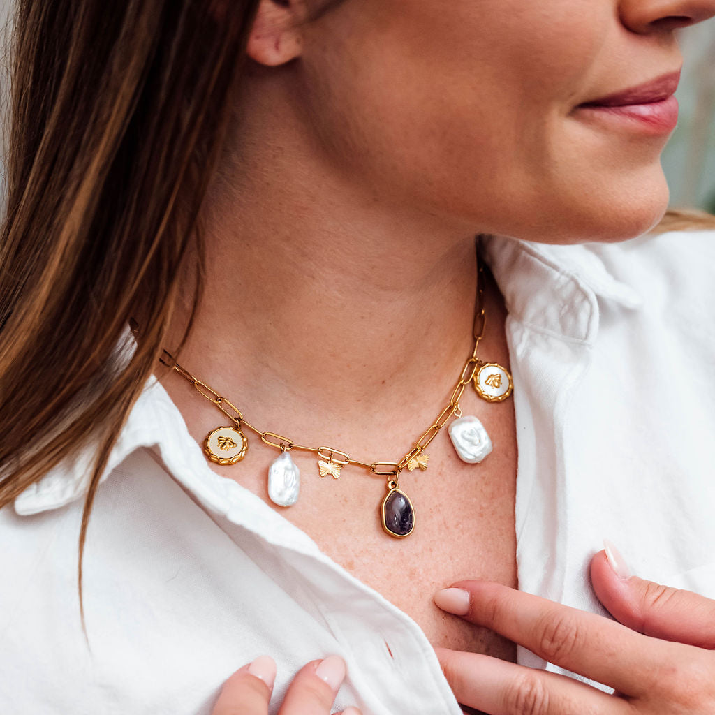 Close-up of a woman wearing a gold necklace with various pendants.