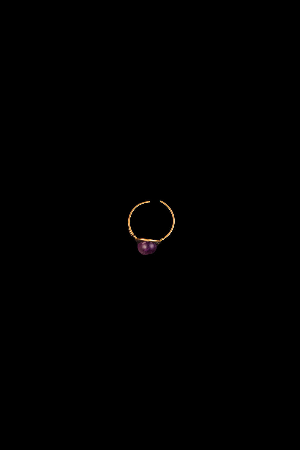 Gold ring with a purple amethyst gemstone on a black background