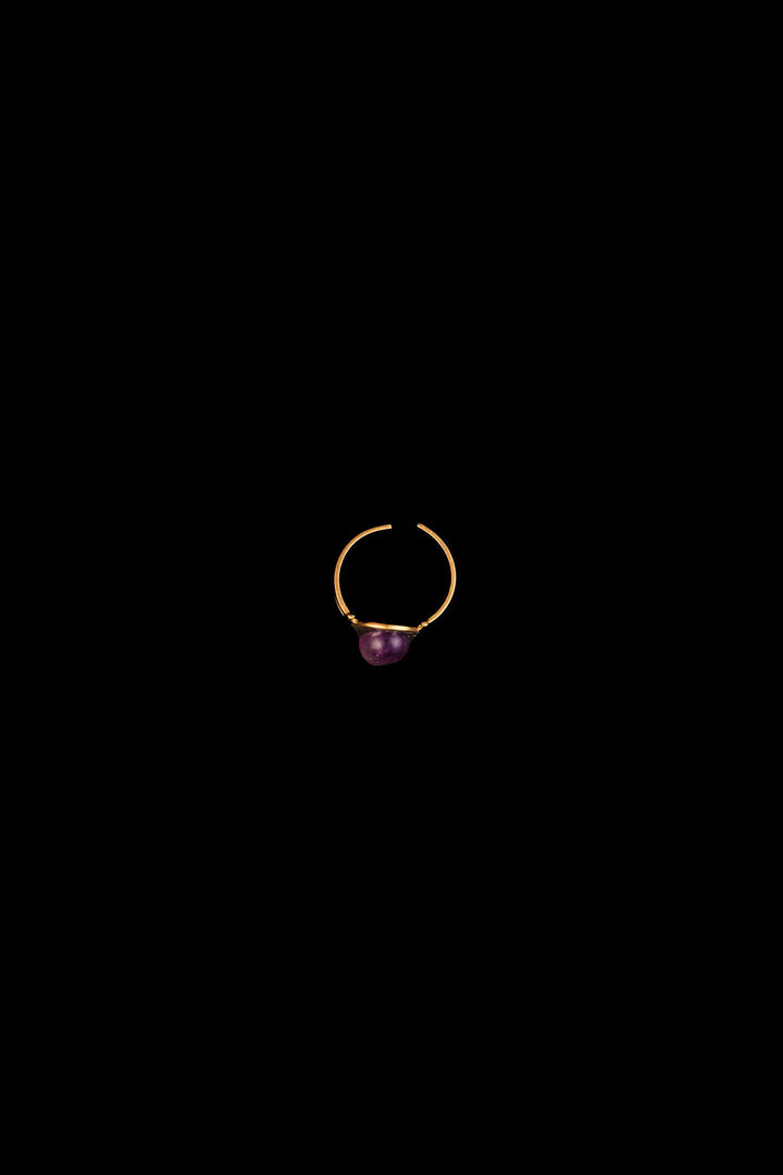 Gold ring with a purple amethyst gemstone on a black background