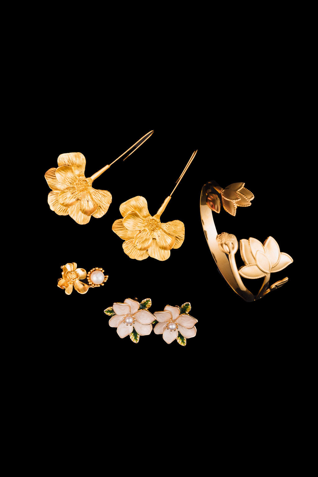 Set of gold magnolia  floral jewelry pieces on a black background
