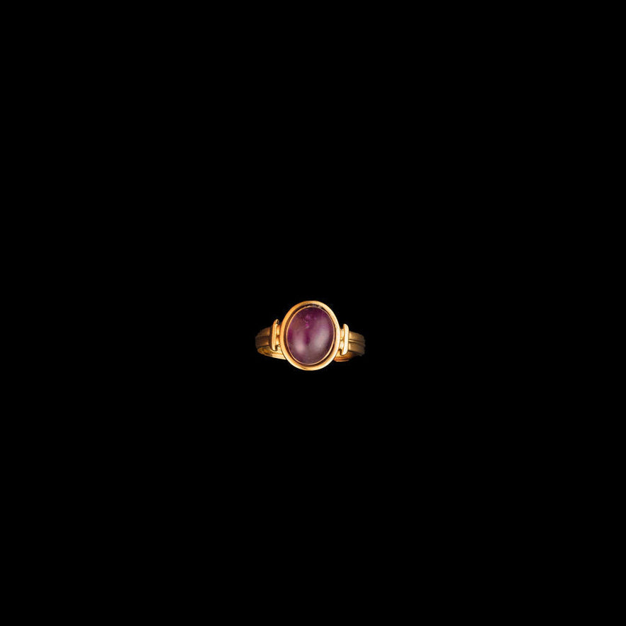 Gold ring with a purple amethyst gemstone on a black background
