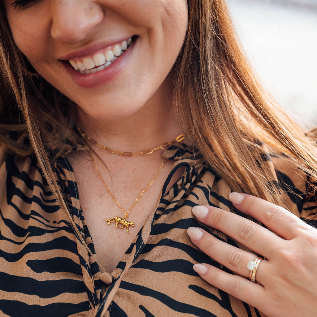 Woman wearing a gold necklace and ring, with a blurred background