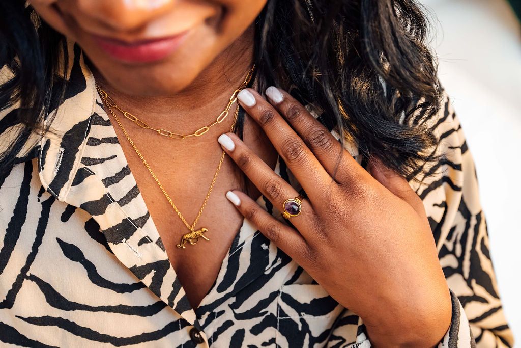 Woman wearing gold  tiger necklaces and a ring, with a blurred background