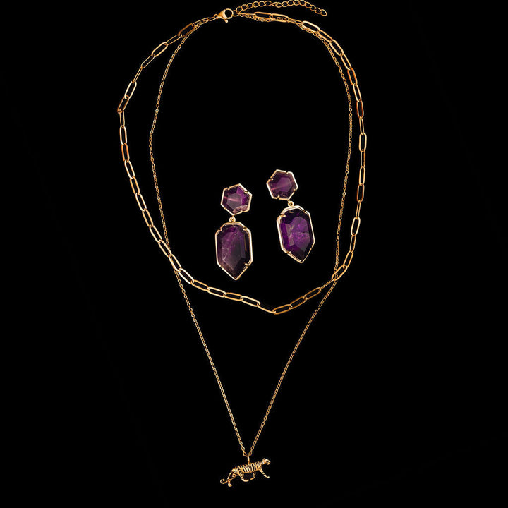 Gold tiger layered necklace with purple amethyst earrings on a black background