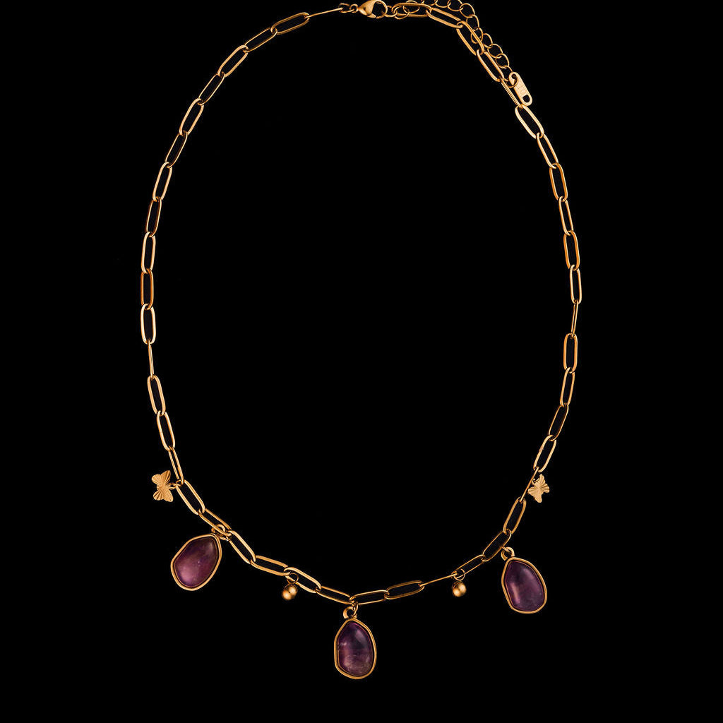 Gold necklace with purple stones on a black background