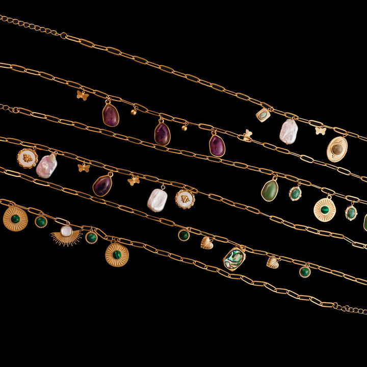 Set of gold necklaces with various gemstone pendants on a black background